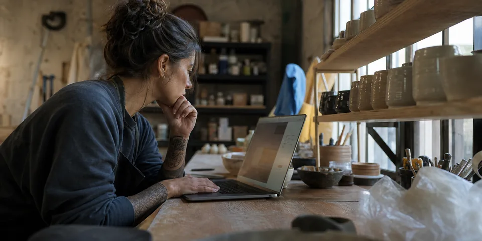 Ceramics studio owner comparing marketing tools on a laptop