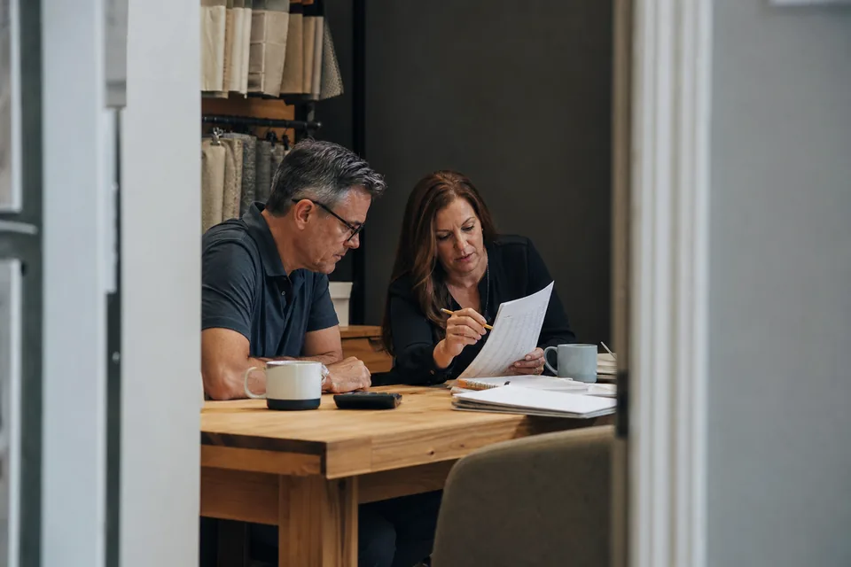 Business owner and finance manager marking up printed figures in a back office
