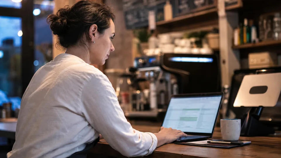 Cafe owner at the counter connecting her accounts on a laptop