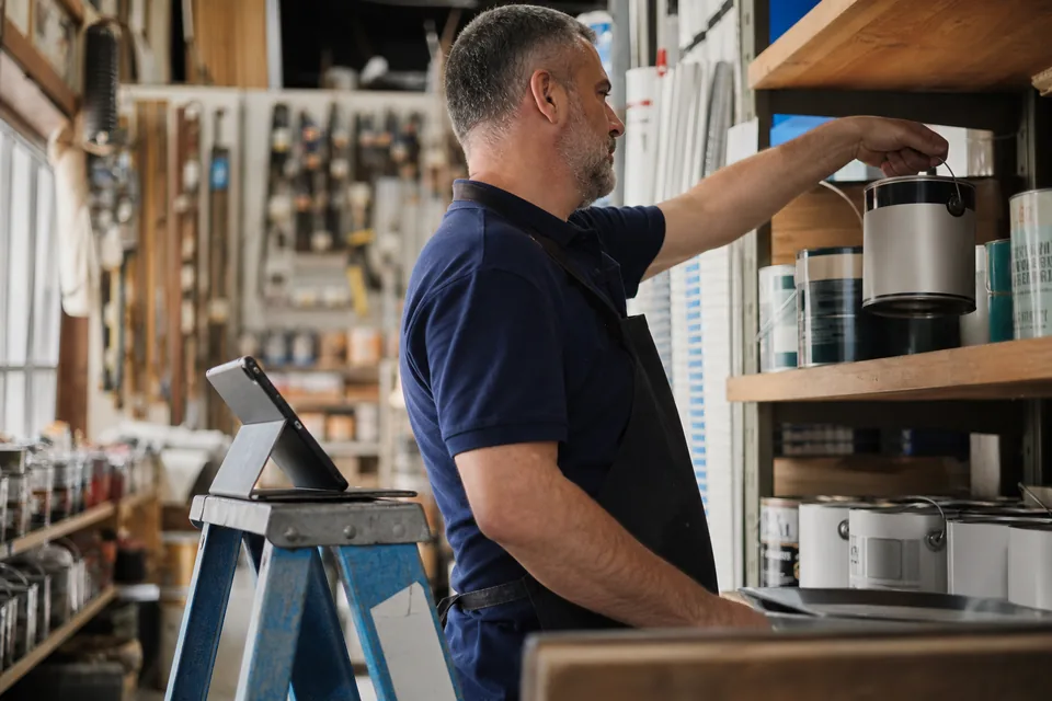 Hardware store owner checking the marketing activity feed on a tablet while restocking