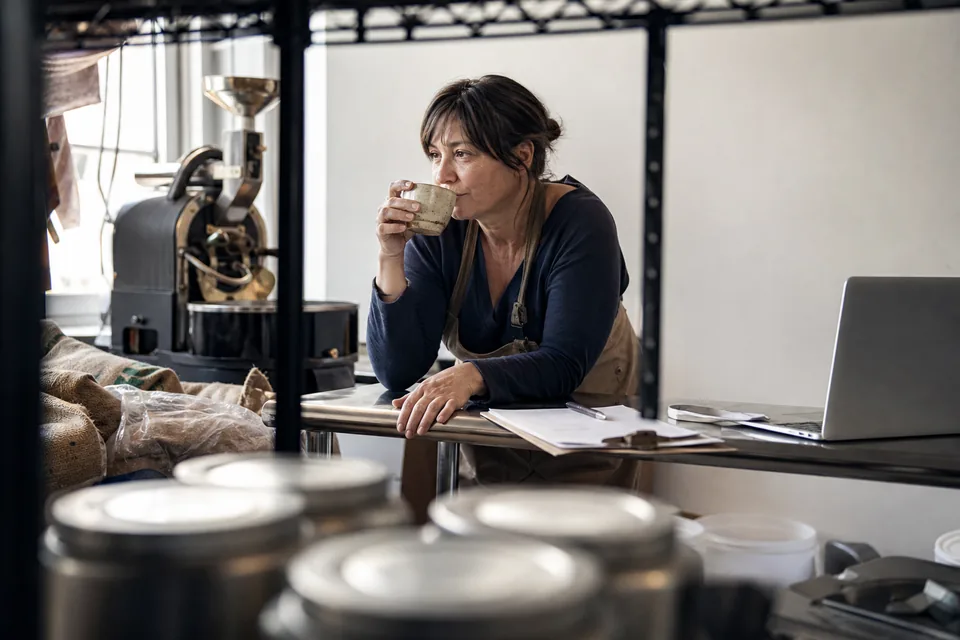 Roastery owner taking a coffee break at her workbench while her marketing runs