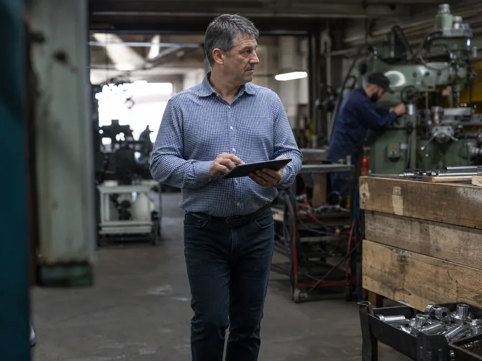 Managing director of a small manufacturer setting priorities on a tablet in the workshop