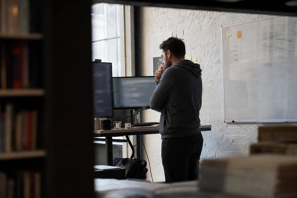 Software founder reading at a standing desk in a converted warehouse office